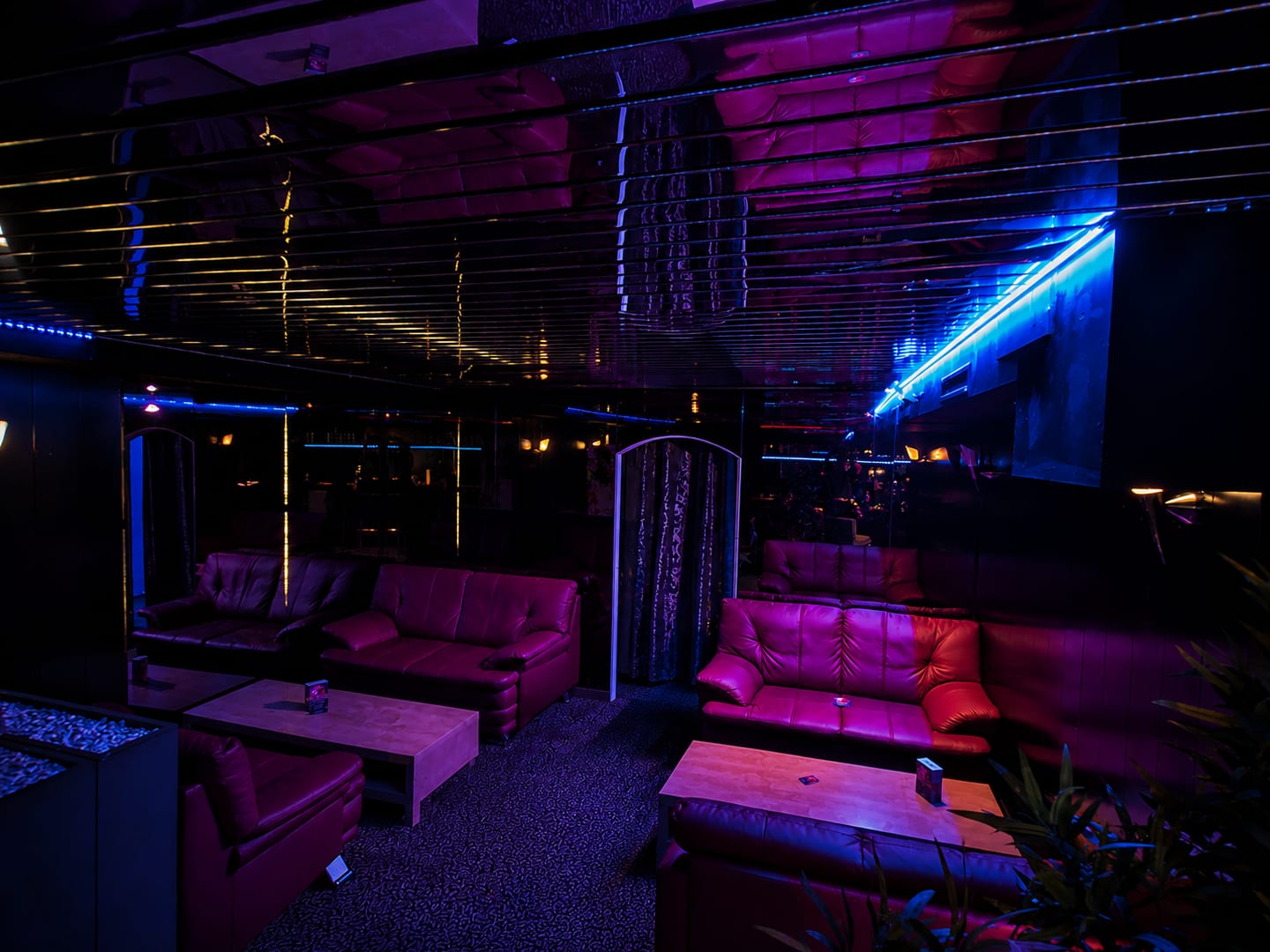 Lounge der Erotik Bar mit Ledersofas, Spiegeldecke und blauem Lichtband