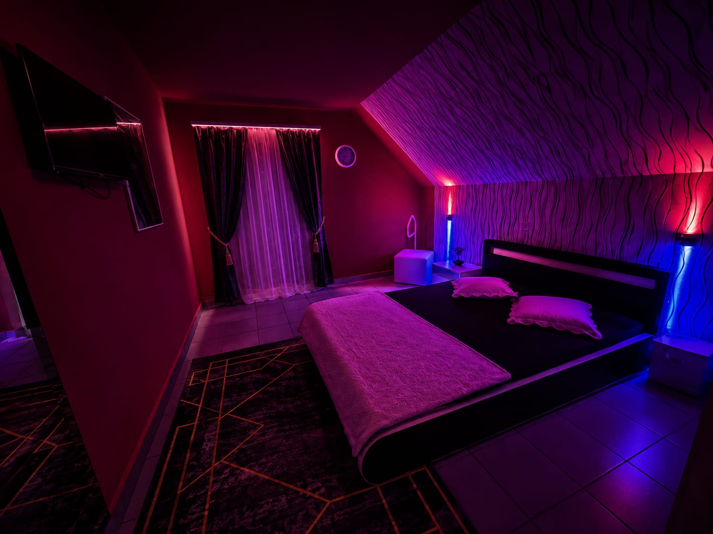 Privates Zimmer mit Doppelbett, Vorhang und Wandleuchten in Rot und Blau